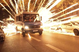 18.10.2023, Berlin: Feuerwerkskörper fliegen hinter einem Polizeiauto bei einer nicht angekündigten pro-palästinensischen Demonstration
