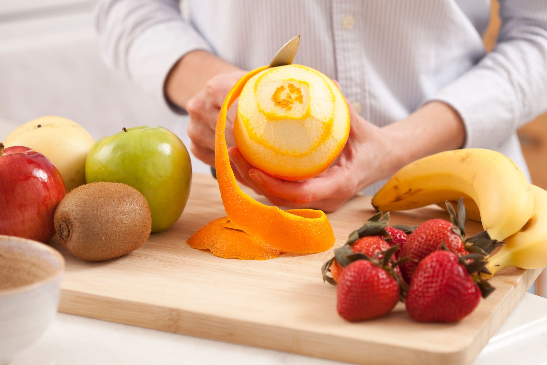 Eine Frau schält eine Orange: Die Schale von Bananen, aber auch von Zitrusfrüchten wie Orangen, ist häufig pestizidbelastet.