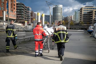 Einsatzkräfte der Hamburger Feuerwehr transportieren den Leichnam zu einem Rettungswagen: Die Hintergründe sind noch unklar.