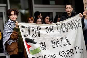 Studenten nehmen an einer Kundgebung für Palästina mit einem Banner "Stop the genocide in Gaza" an teil