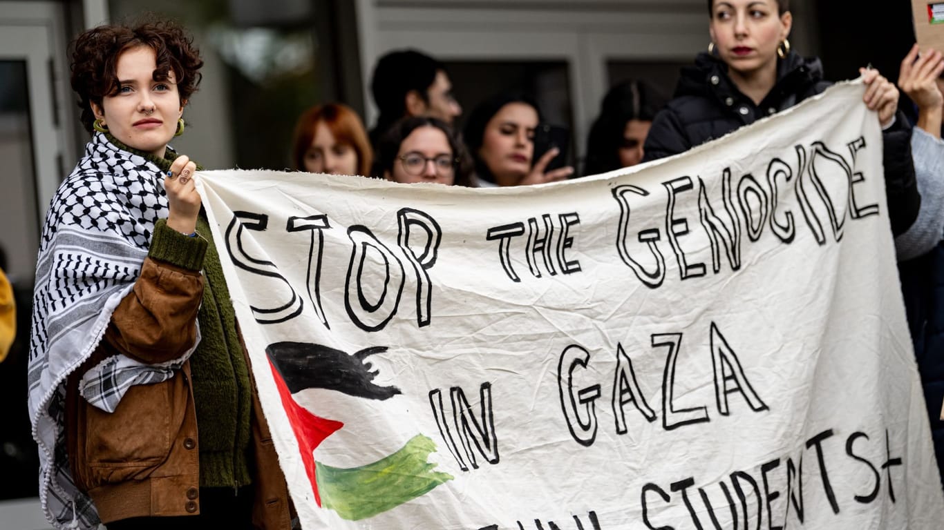 Studenten nehmen an einer Kundgebung für Palästina mit einem Banner "Stop the genocide in Gaza" an teil