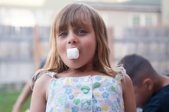 Ein fünfjähriges Mädchen isst einen Marshmallow.