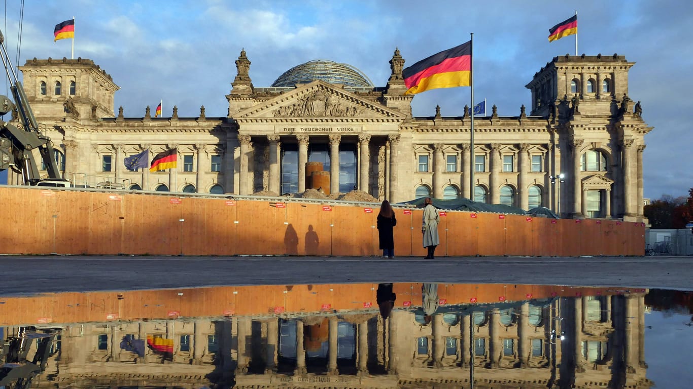 Der Reichstag spiegelt sich in einer Pfütze nach einem Regenguss (Archivbild): Auch in der neuen Wolke bleibt es in Berlin und Brandenburg überwiegend feucht.