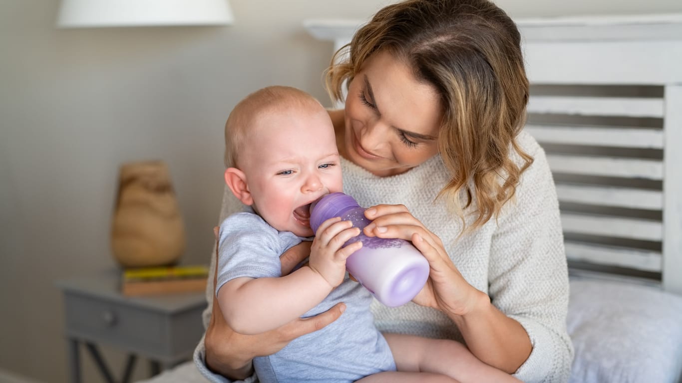 Ein Baby wird mit einer Flasche gefüttert und weint.