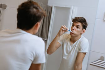 Ein junger Mann putzt sich die Zähne: Ob mit oder ohne Erkältung: Die Zahnbürste regelmäßig zu wechseln, sollte Teil der Mundhygiene sein.