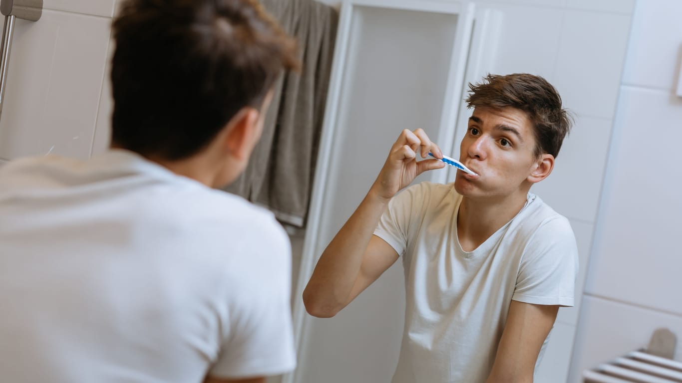 A young man brushes his teeth: Whether with or without a cold: changing your toothbrush regularly should be part of your oral hygiene.