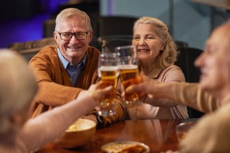 Eine Gruppe älterer Menschen stößt mit Bier an.