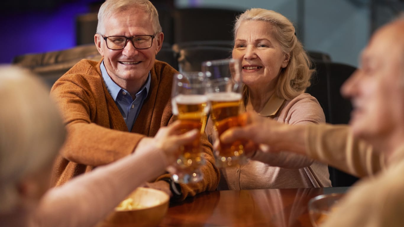 Eine Gruppe älterer Menschen stößt mit Bier an.