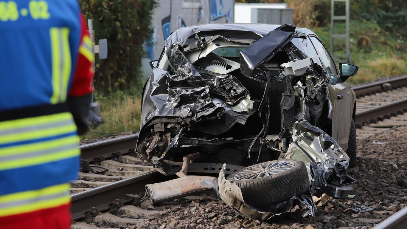 Der völlig zerstörte Pkw steht auf Zuggleisen: Der Fahrer konnte sich rechtzeitig in Sicherheit bringen.