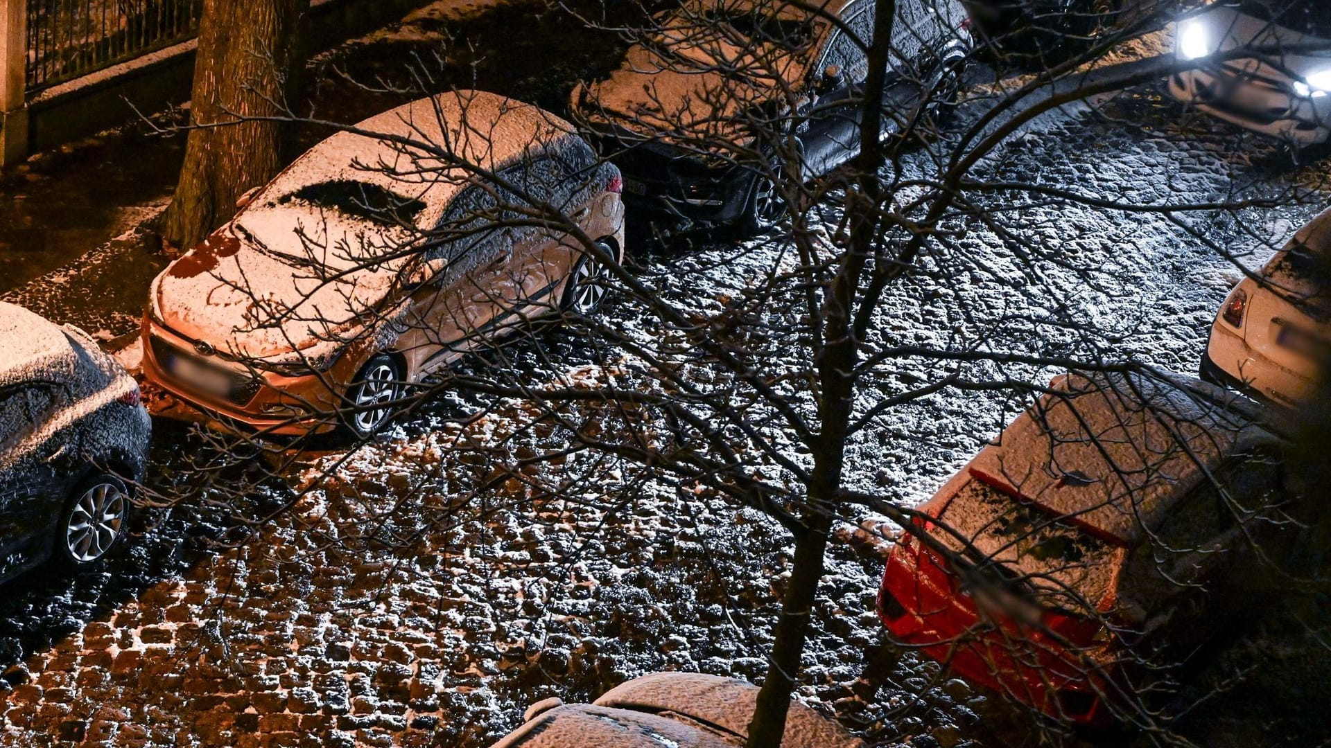 Ein Auto fährt am späten Abend durch eine schneebedeckte Straße in Karlshorst.