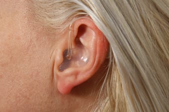 Eine Frau mit Hörgerät (Symbolbild): Nahaufnahme vom Hörgerät im Ohr.