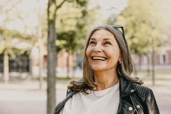 Eine Frau schaut fröhlich (Symbolbild): Wann Sie in Rente gehen können, hängt nicht nur von Ihrem Alter ab.