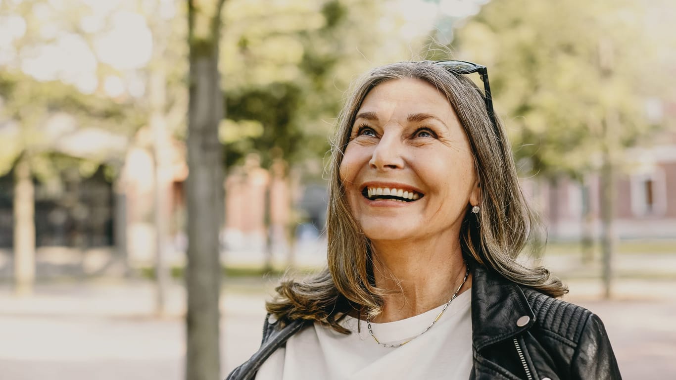 Eine Frau schaut fröhlich (Symbolbild): Wann Sie in Rente gehen können, hängt nicht nur von Ihrem Alter ab.