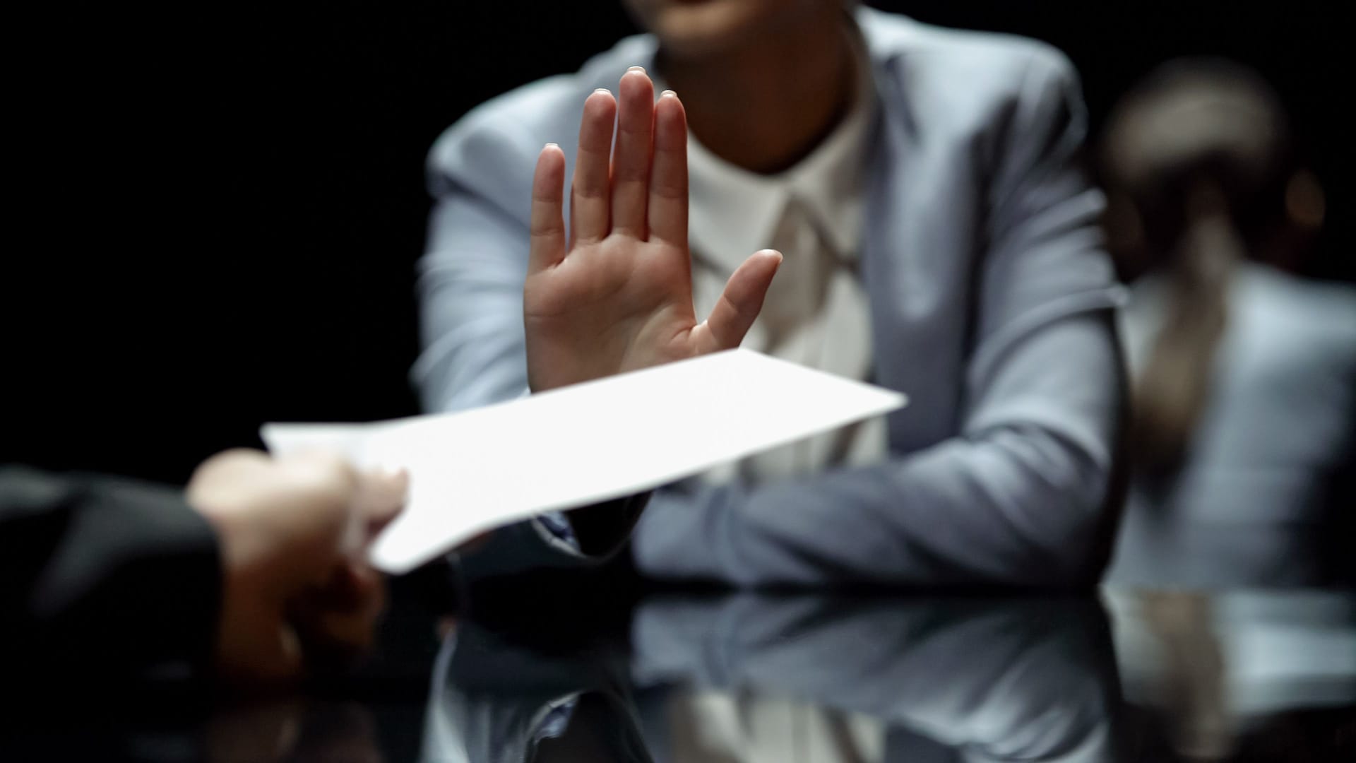 Eine Person lehnt ein Dokument ab. Eine Person lehnt ein Dokument ab.