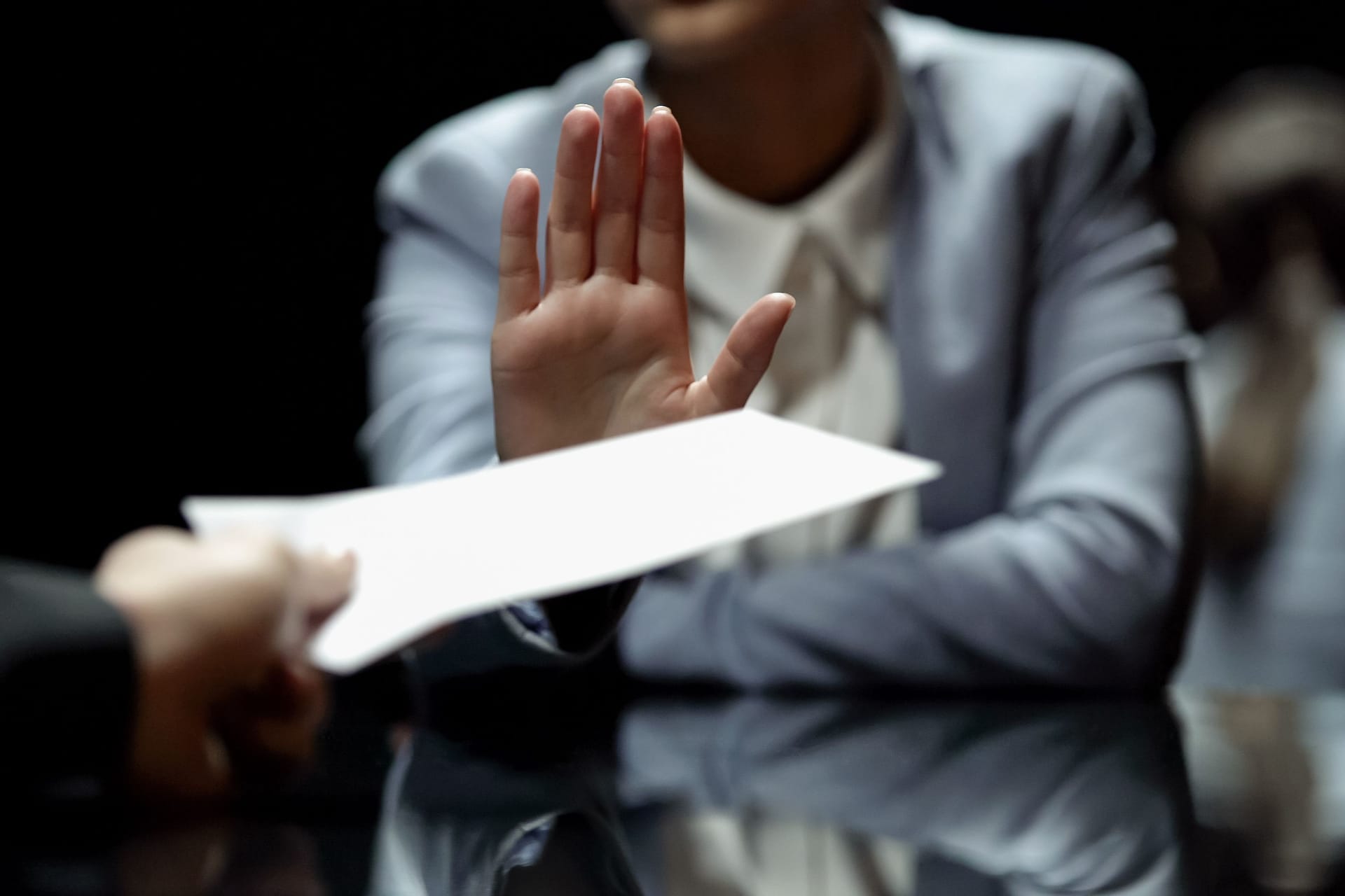 Eine Person lehnt ein Dokument ab. Eine Person lehnt ein Dokument ab.