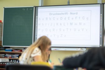 Schüler vor einer Tafel mit digitalem Whiteboard (Symbolbild): Eine Initiative fordert die Rückkehr zu alten Lernmitteln.