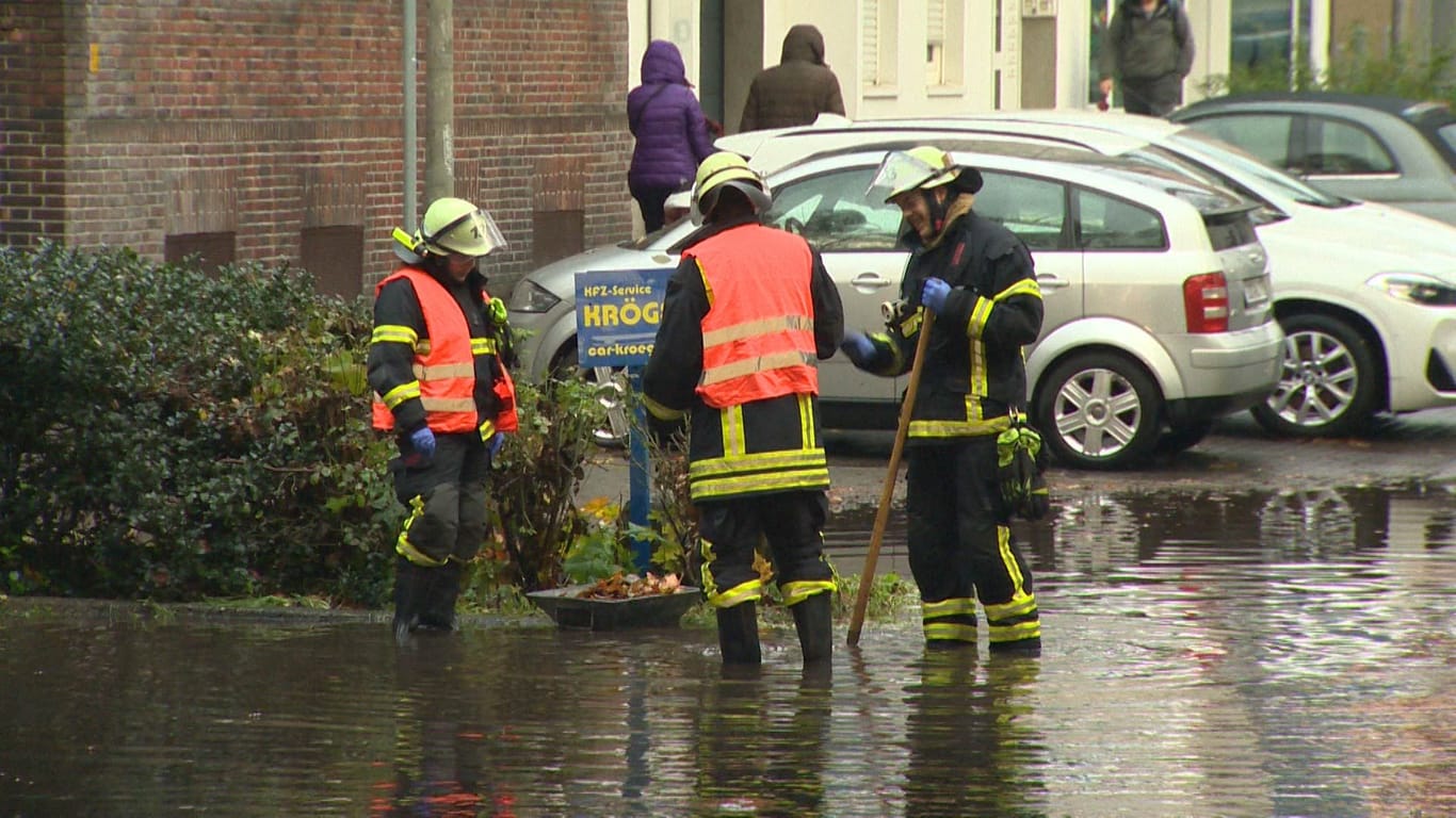 Feuerwehrleute befreien Gullis auf Dortmunder Straßen von den Wassermassen.
