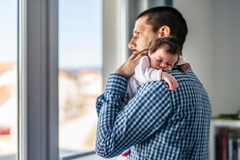 Mann mit neugeborenem Baby: Neugeborene haben häufig mehrmals täglich Schluckauf.