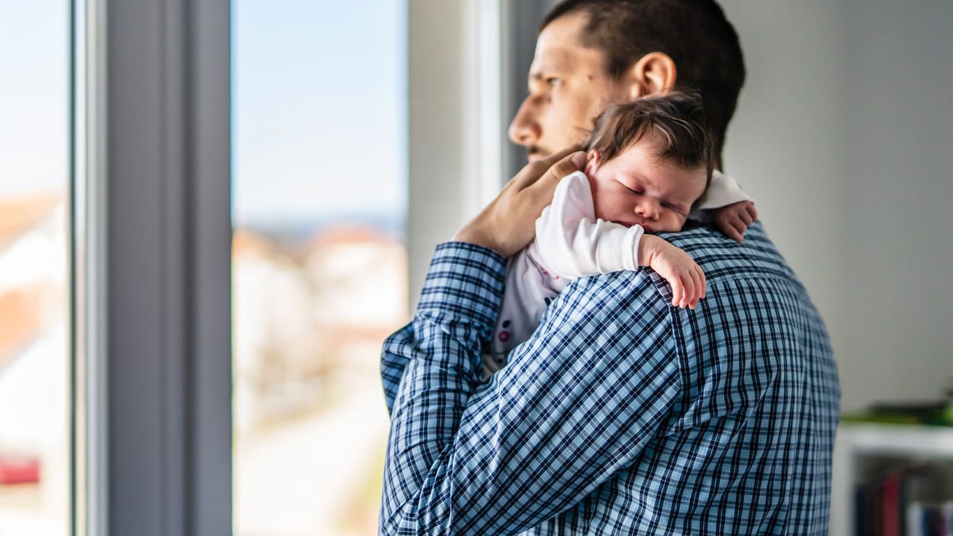 Mann mit neugeborenem Baby: Neugeborene haben häufig mehrmals täglich Schluckauf.