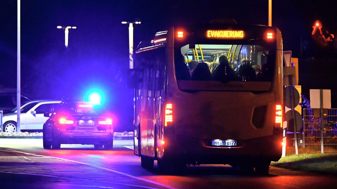 Ein Polizeiauto mit Blaulicht eskortiert einen Bus voll Menschen: Tausende Reisende mussten vom Flughafen weggebracht werden.