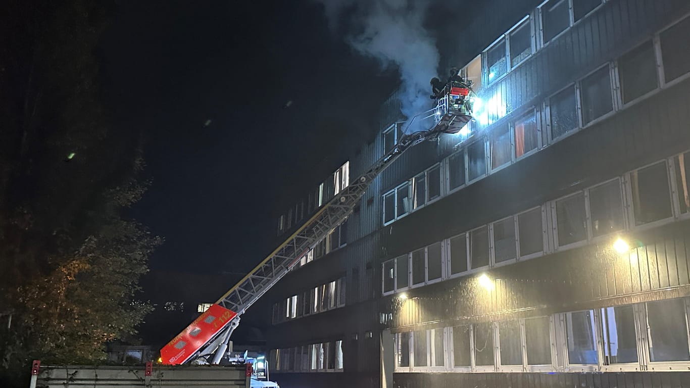 Feuerwehrleute stehen auf einer Drehleiter vor der brennenden Wohnung: Der Bewohner konnte noch rechtzeitig gerttet werden.