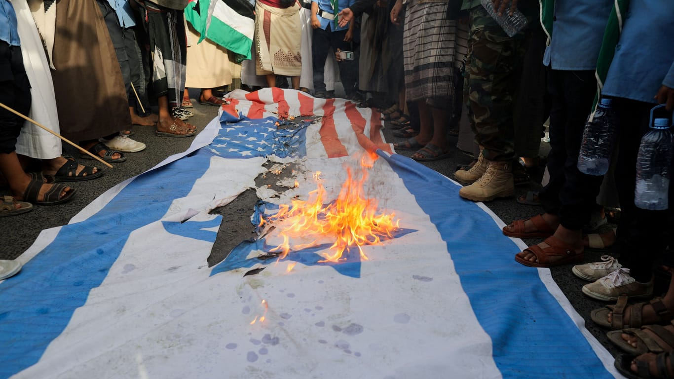 Demonstrierende und Huthi-Anhänger verbrennen eine Israel-Fahne: Die Ideologie der Huthis ist zutiefst antisemitisch und anti-israelisch.