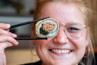 Christin Hamer-Osburg, Serviceleiterin im Restaurant Moto Kitchen, hält Sushi mit Grünkohl und Pinkel in den Händen.