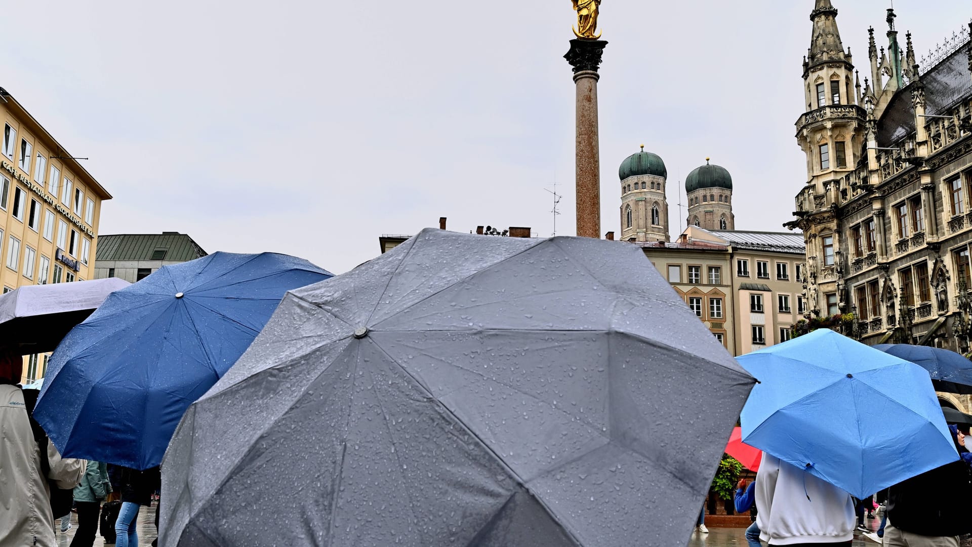 Menschen schlendern mit Regenschirmen über den Marienplatz (Symbolbild): Auch am Mittwoch bleibt es in München weiter ungemütlich.