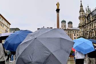 Menschen schlendern mit Regenschirmen über den Marienplatz (Symbolbild): Auch am Mittwoch bleibt es in München weiter ungemütlich.