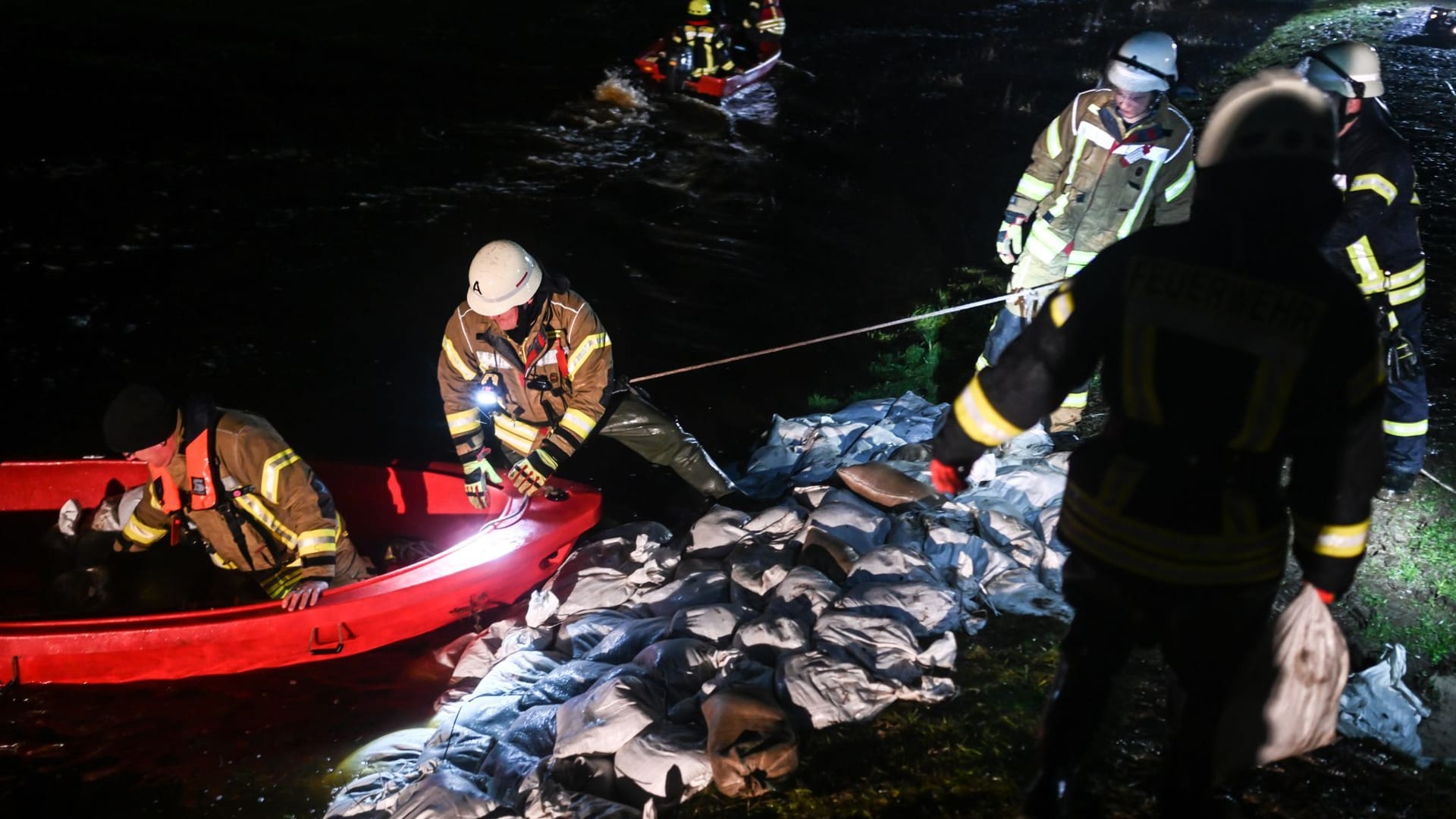 Einsatzkräfte flicken die Löcher im Deich mit gefüllten Sandsäcken: An mehreren Orten sich Deiche aufgeweicht.