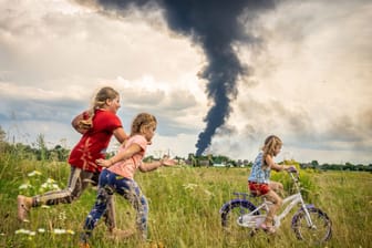 Ukraine: Unter den dunklen Wolken des Krieges übt die fünfjährige Alina, begleitet von Freundinnen, das Fahrradfahren auf einer Wiese im Nordwesten der Ukraine.