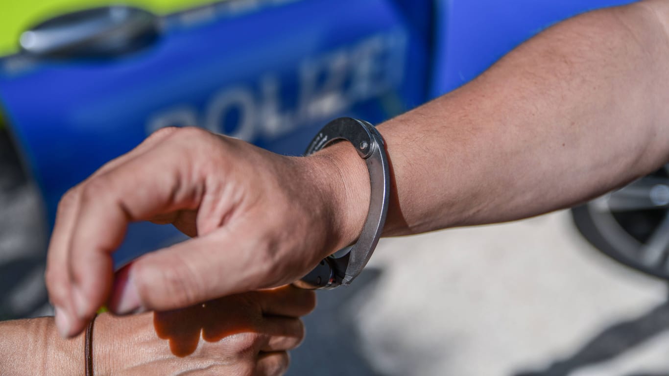 Ein Polizist legt einem Mann Handschellen an (Symbolbild).