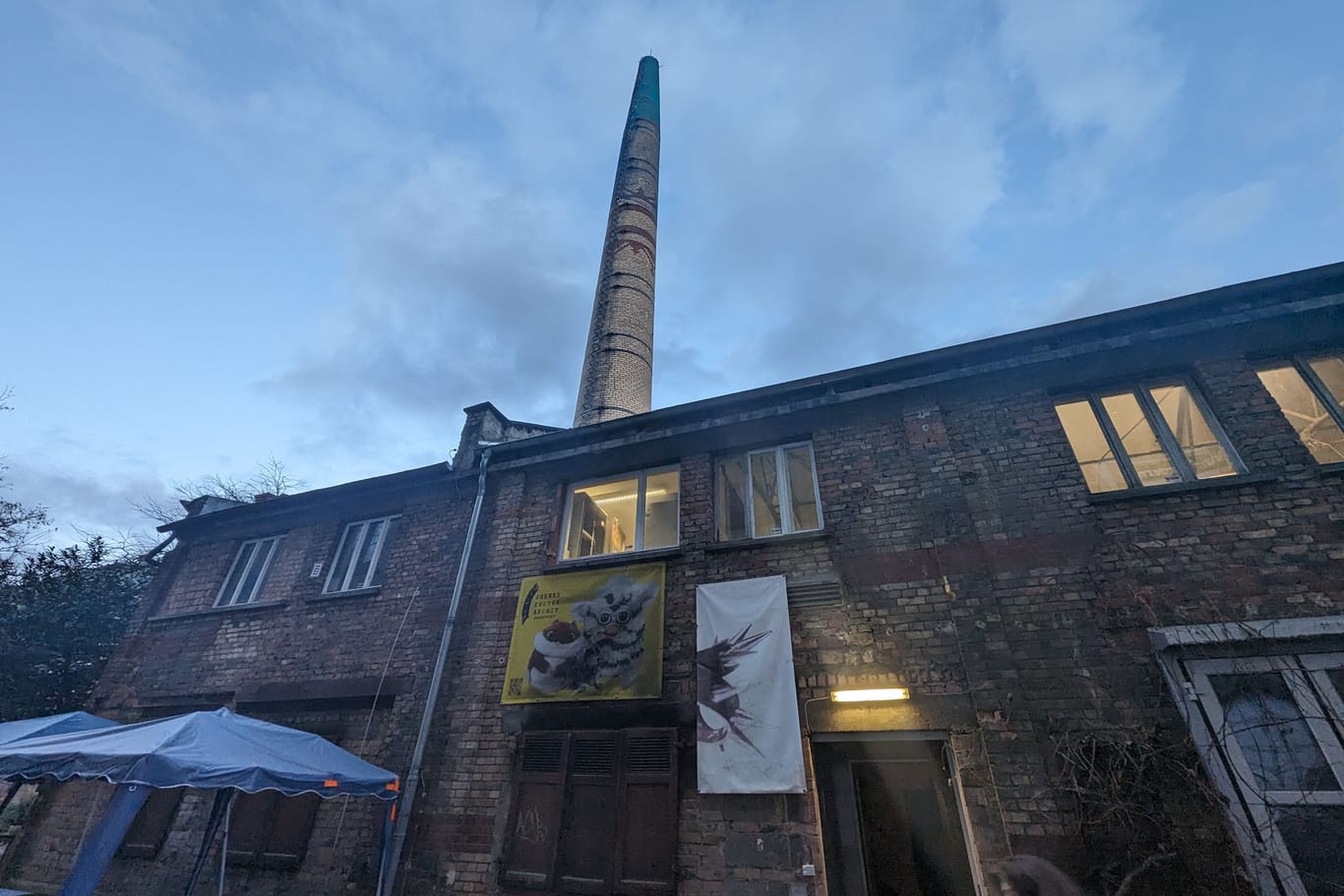 Dondorf-Druckerei Außenansicht in der Dämmerung. Zu sehen ist der Historische Schornstein aus Backstein.