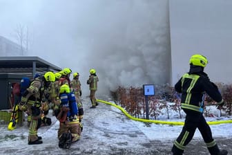 Einsatzkräfte der Feuerwehr löschen einen Brand in einem Wohnhaus in Berlin-Hellersdorf