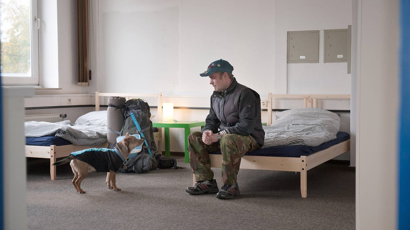 Ein Mann mit seinem Hund in einer Notunterkunft (Archivbild): Hamburg passt die Öffnungszeiten seiner Notunterkünfte an.