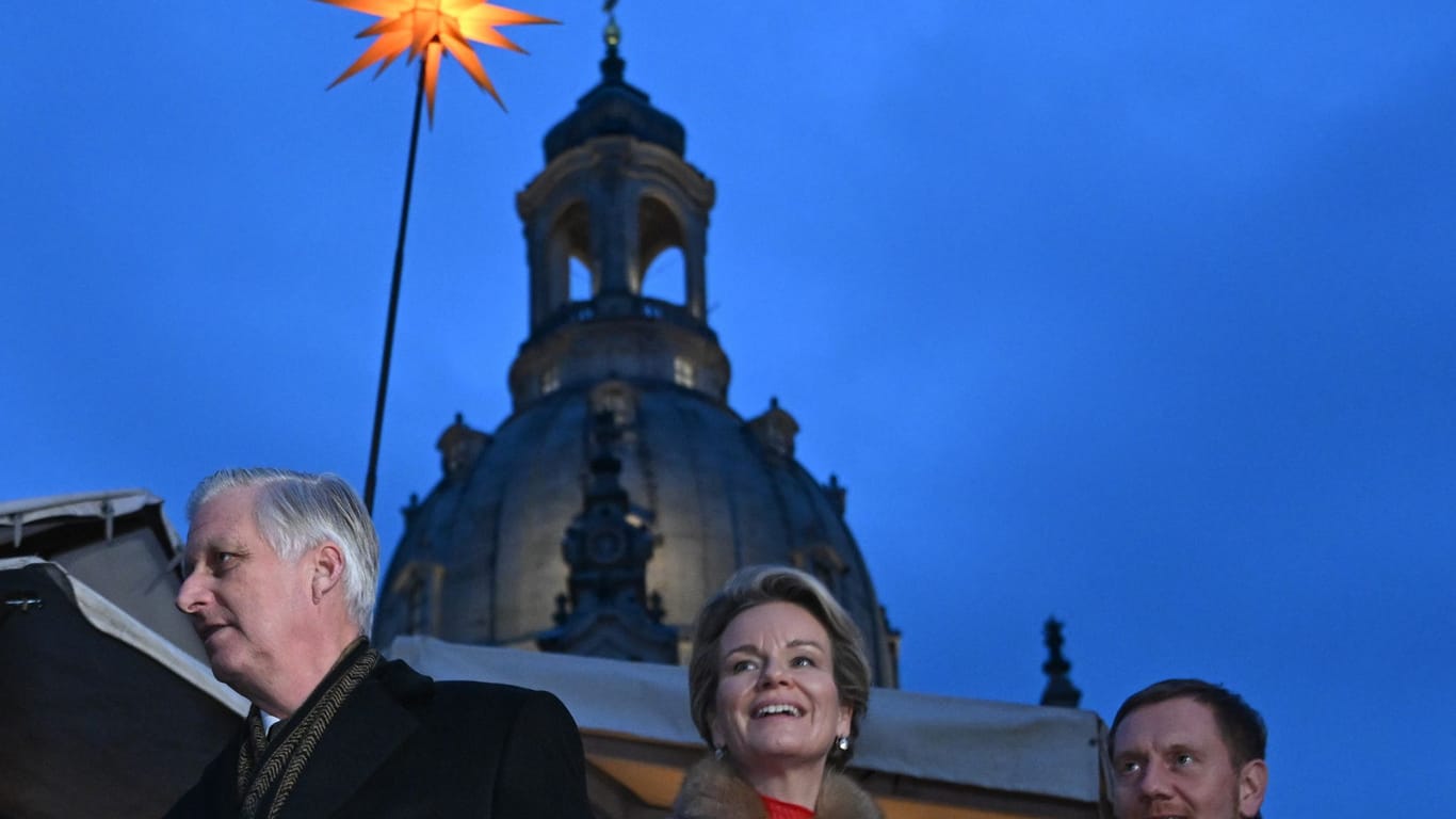 König Philippe und Königin Mathilde der Belgier gehen mit Michael Kretschmer (CDU), Ministerpräsident von Sachsen, über den Weihnachtsmarkt auf dem Neumarkt vor der Frauenkirche.