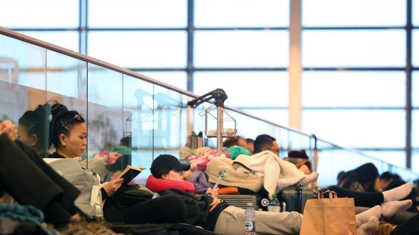 Passagiere warten am Münchner Flughafen: Dort läuft der Betrieb wieder an, aber vor allem beim öffentlichen Nahverkehr geht das Chaos weiter.