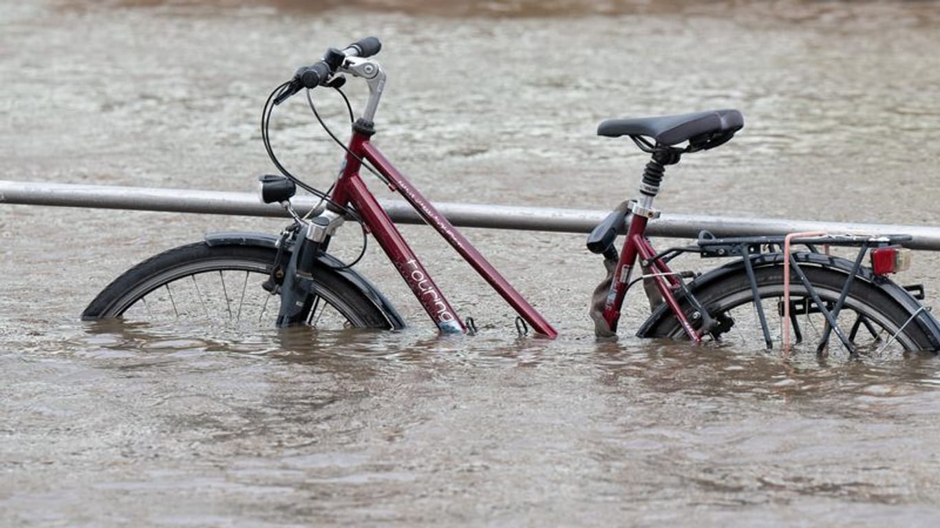 Das Hochwasser der Elbe umgibt ein Fahrrad am Terrassenufer: Wegen Überflutungen sind derzeit in mehreren Orten Sachsens Straßen gesperrt.