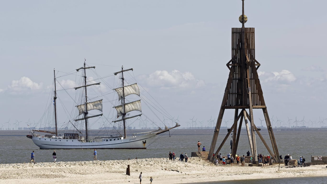 Ein Segelschiff vor der Kugelbake, dem Wahrzeichen von Cuxhaven.