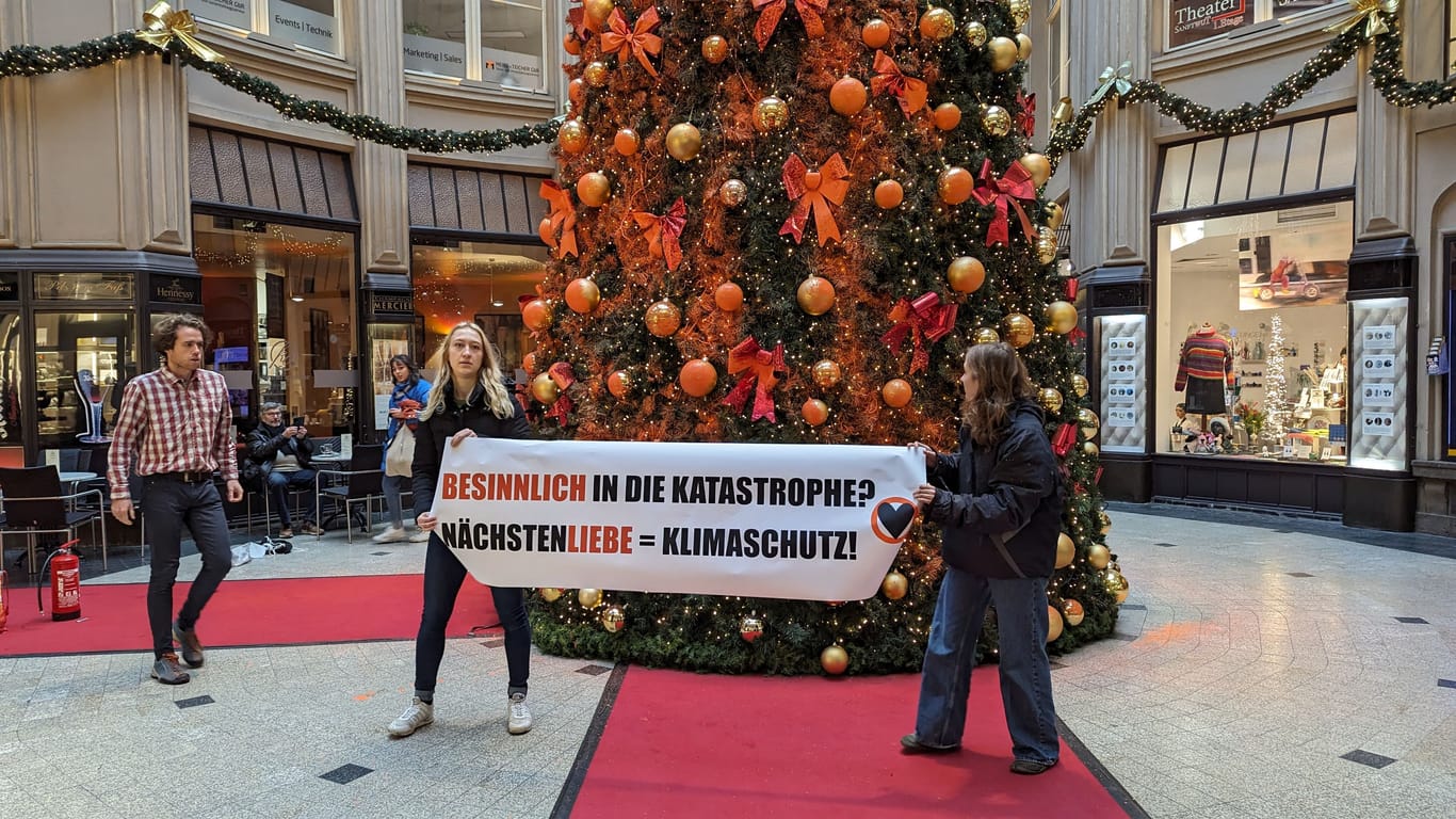 Klimaaktivisten entrollen ein Banner vor dem Weihnachtsbaum in Leipzig: