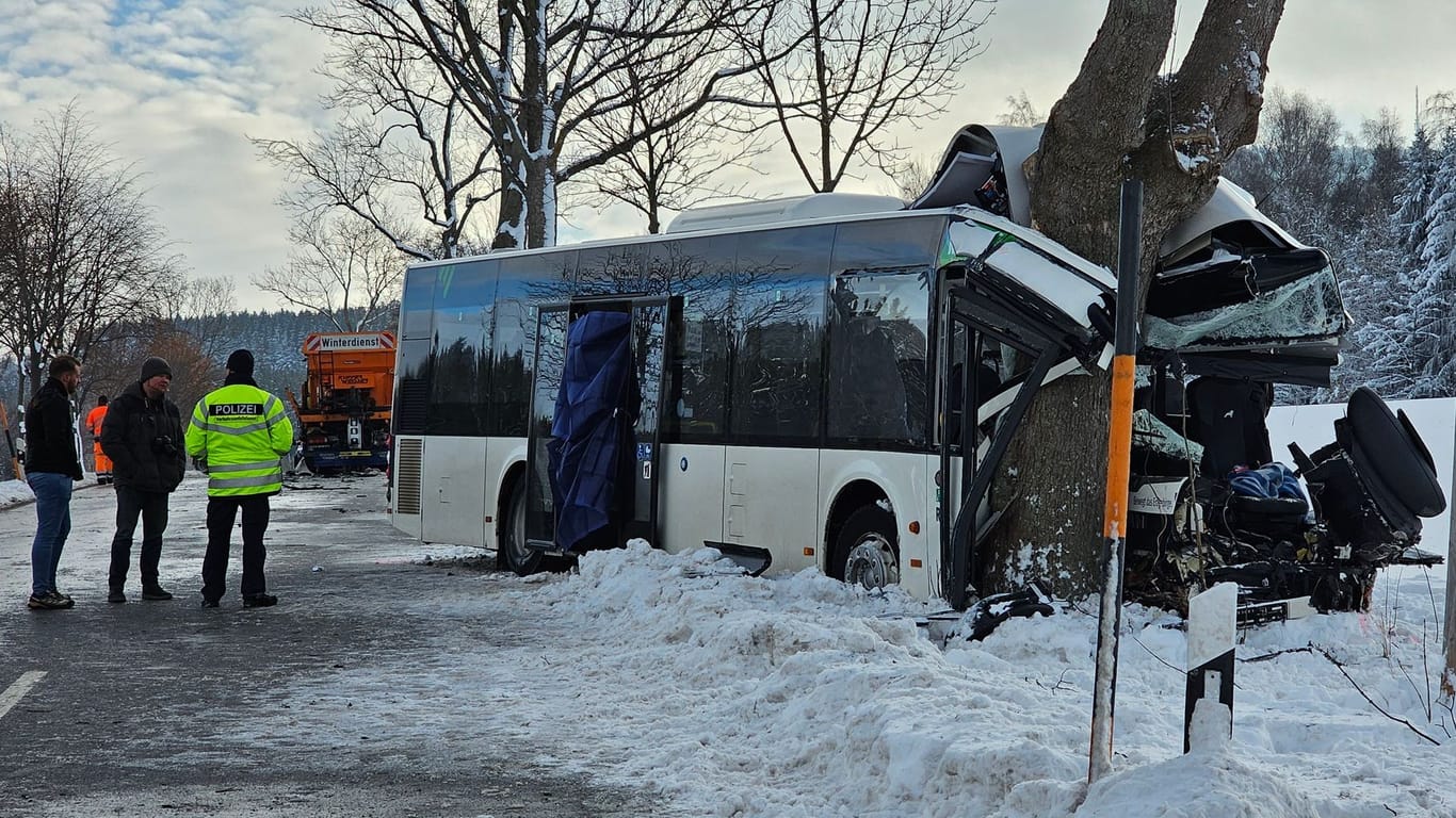 Einsatzkräfte an verunglücktem Bus: Bei dem Unfall im Erzgebirge ist am Dienstagmorgen ein Kind getötet worden. 12 Menschen wurden verletzt, zwei davon schwer.