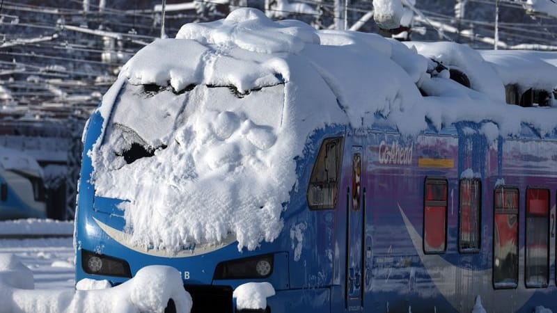 Ein mit Schnee bedeckter Regionalzug steht im Hauptbahnhof im München.