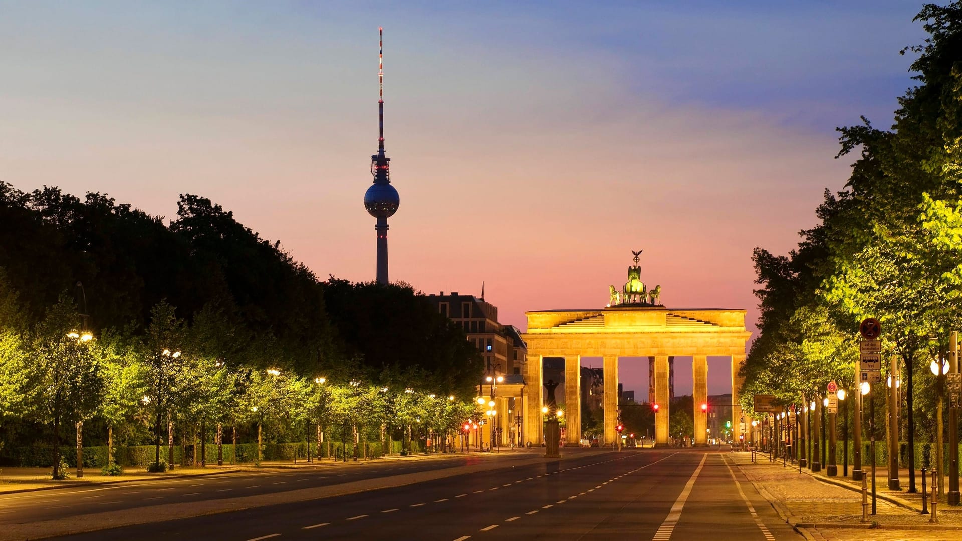 Leere Straße des 17. Juni im Morgenrot mit Brandenburger Tor und Berliner Fernsehturm