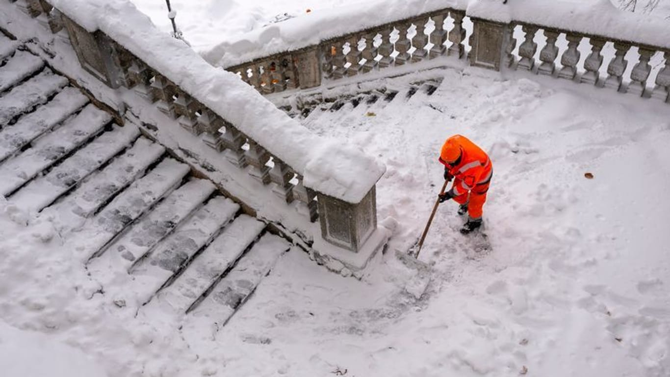 Ein Mitarbeiter der Münchner Stadtreinigung schippt am Friedensengel Schnee von der Freitreppe