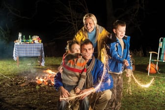 Familie zu Silvester im Garten zündet Feuerwerk an