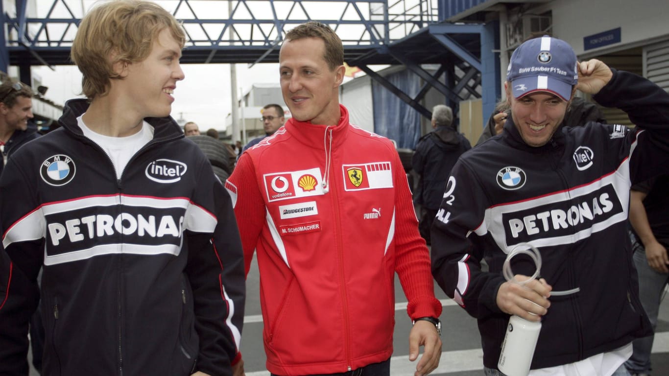 Sebastian Vettel (l.) neben Michael Schumacher (m.) vor einem Rennen im Jahr 2006.