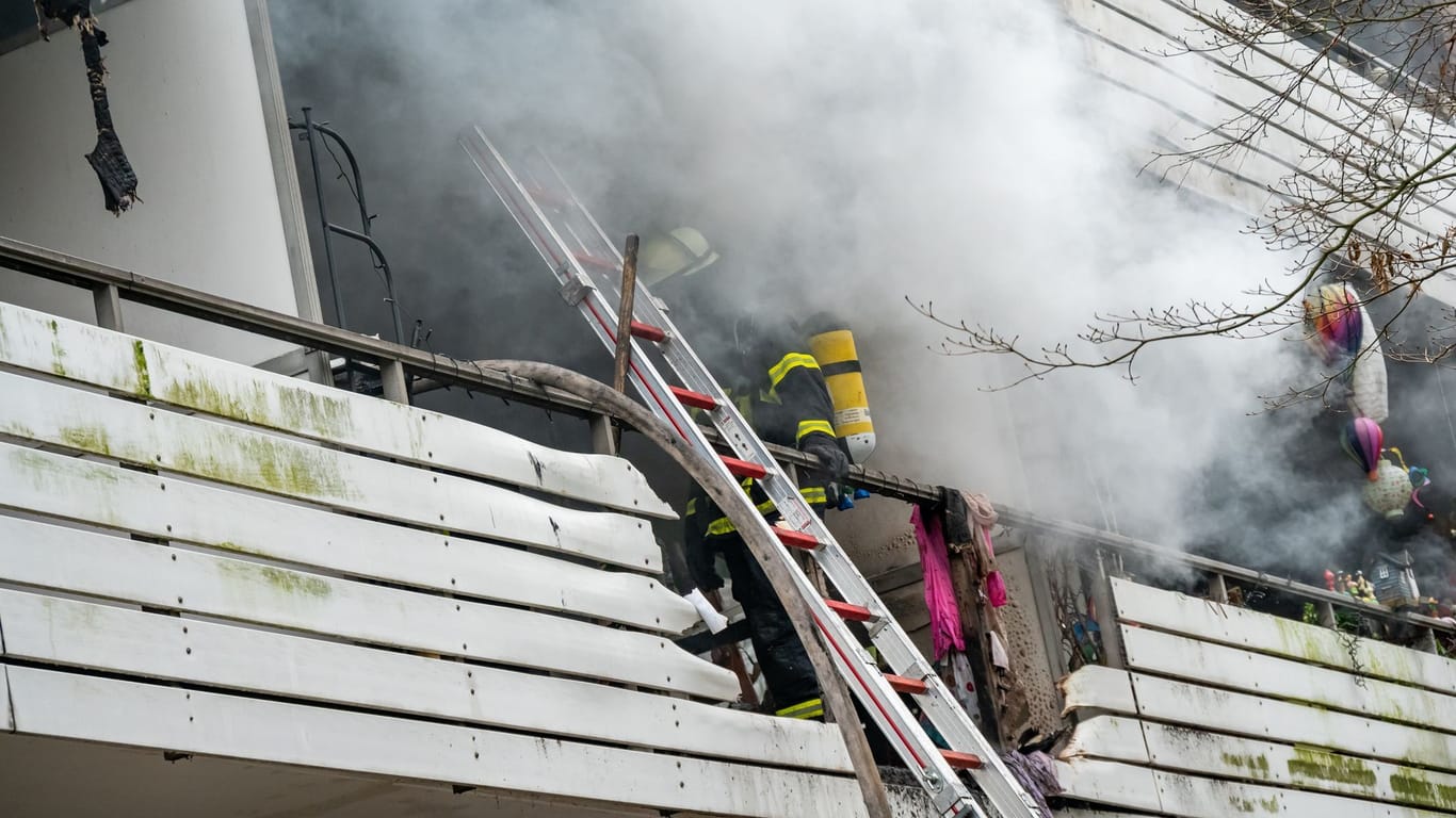 Ein Atemschutzträger der Feuerwehr steht im starken Rauch auf dem Balkon der Brandwohnung.
