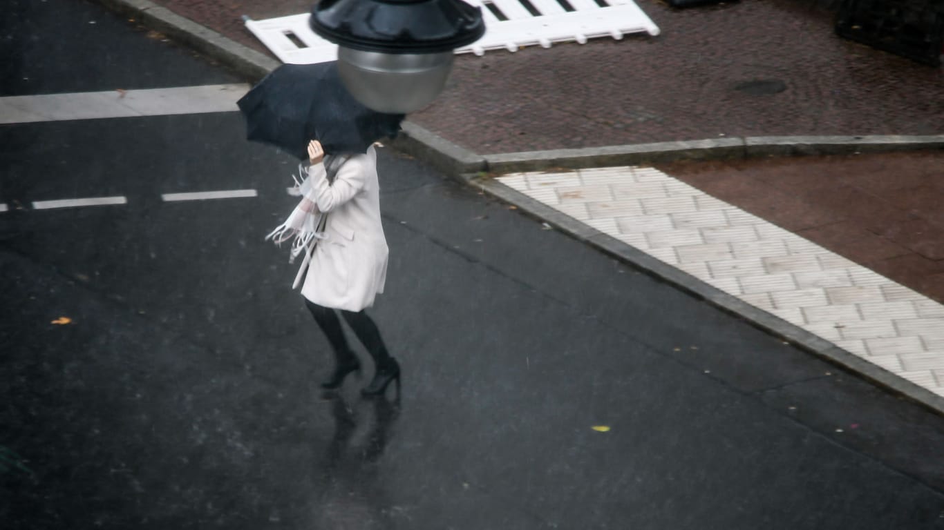 Eine Frau rennt mit Regenschirm durch Berlin (Archivbild): In der Hauptstadt und in Brandenburg wird es ungemütlich.