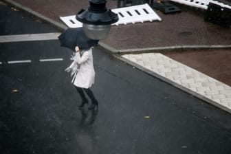 Eine Frau rennt mit Regenschirm durch Berlin (Archivbild): In der Hauptstadt und in Brandenburg wird es ungemütlich.