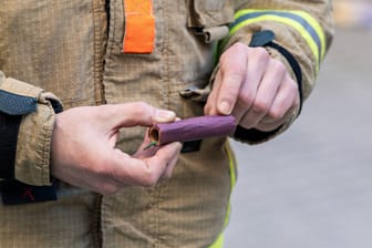 Feuerwehrmann mit Böller in den Händen (Archivbild): Experten warnen vor verantwortungslosem Umgang mit Silvesterknallern.
